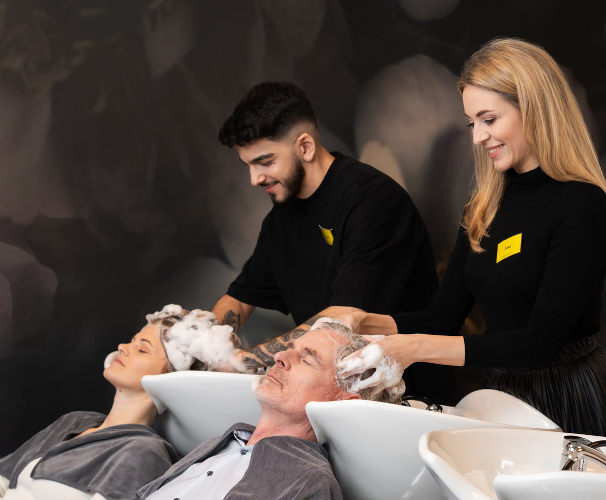 Haarwäsche KLIPP Zwei Friseure waschen zwei Kunden die Haare