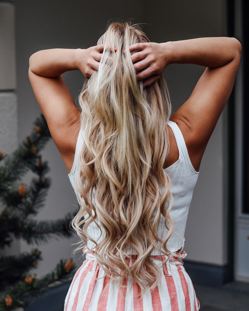 Frau-fährt-sich-mit-ihren-Händen-durch-ihr-verlängertes-Haar Frau-fährt-sich-mit-ihren-Händen-durch-ihr-verlängertes-Haar
